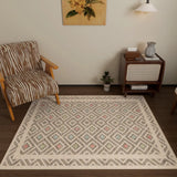 A cozy living room with a brown striped armchair, the Geo Sand Washable Rug (JRN1027), a mid-century side table with books and a vase, a small plant, wall lamp, and a floral painting on a cream wall.