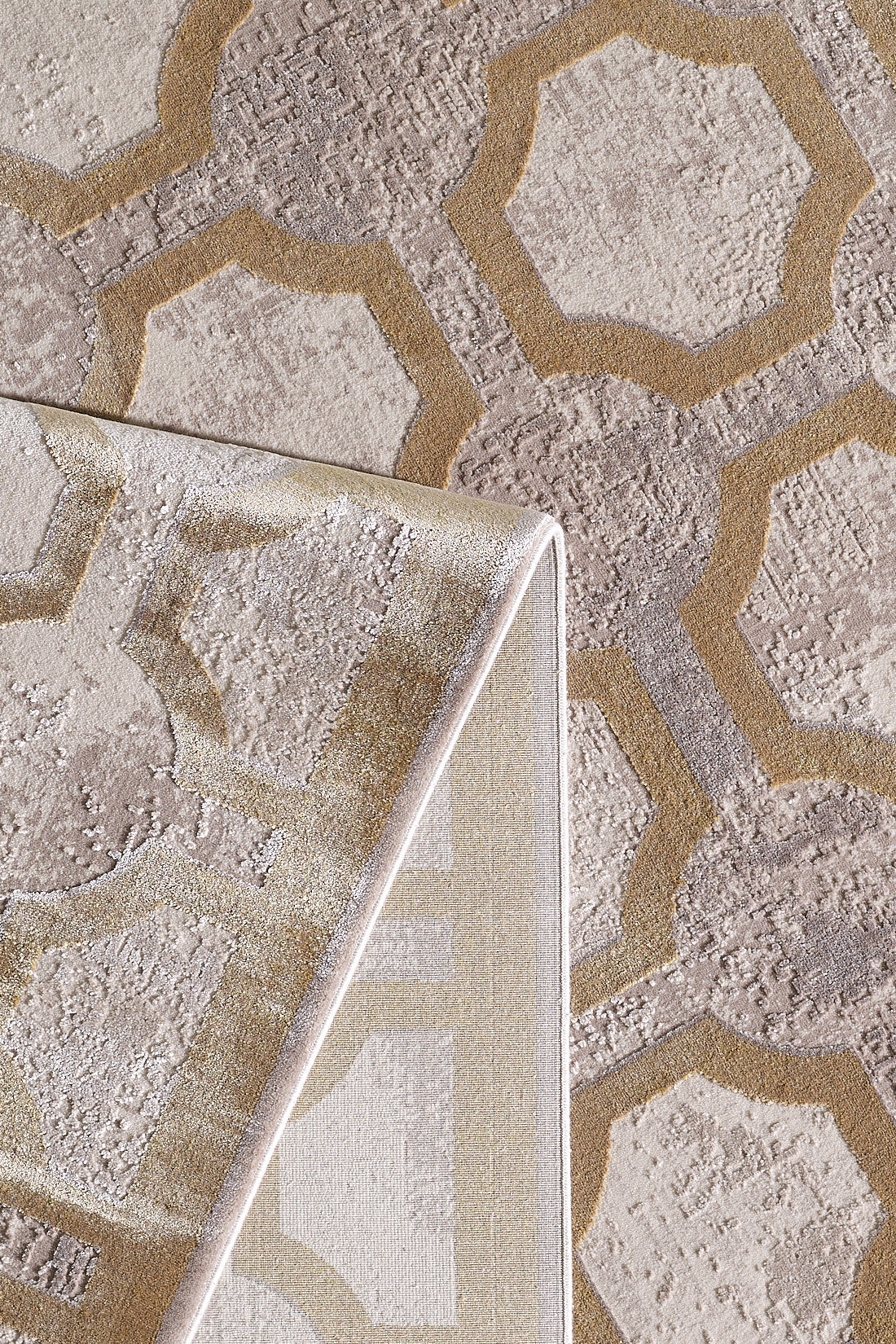 A close-up of the Geometric Down Mid Century Modern Rug - M534B, showcasing its beige, taupe, and gold lattice pattern. One corner is folded to display the rug’s machine-made underside and detailed edge stitching.