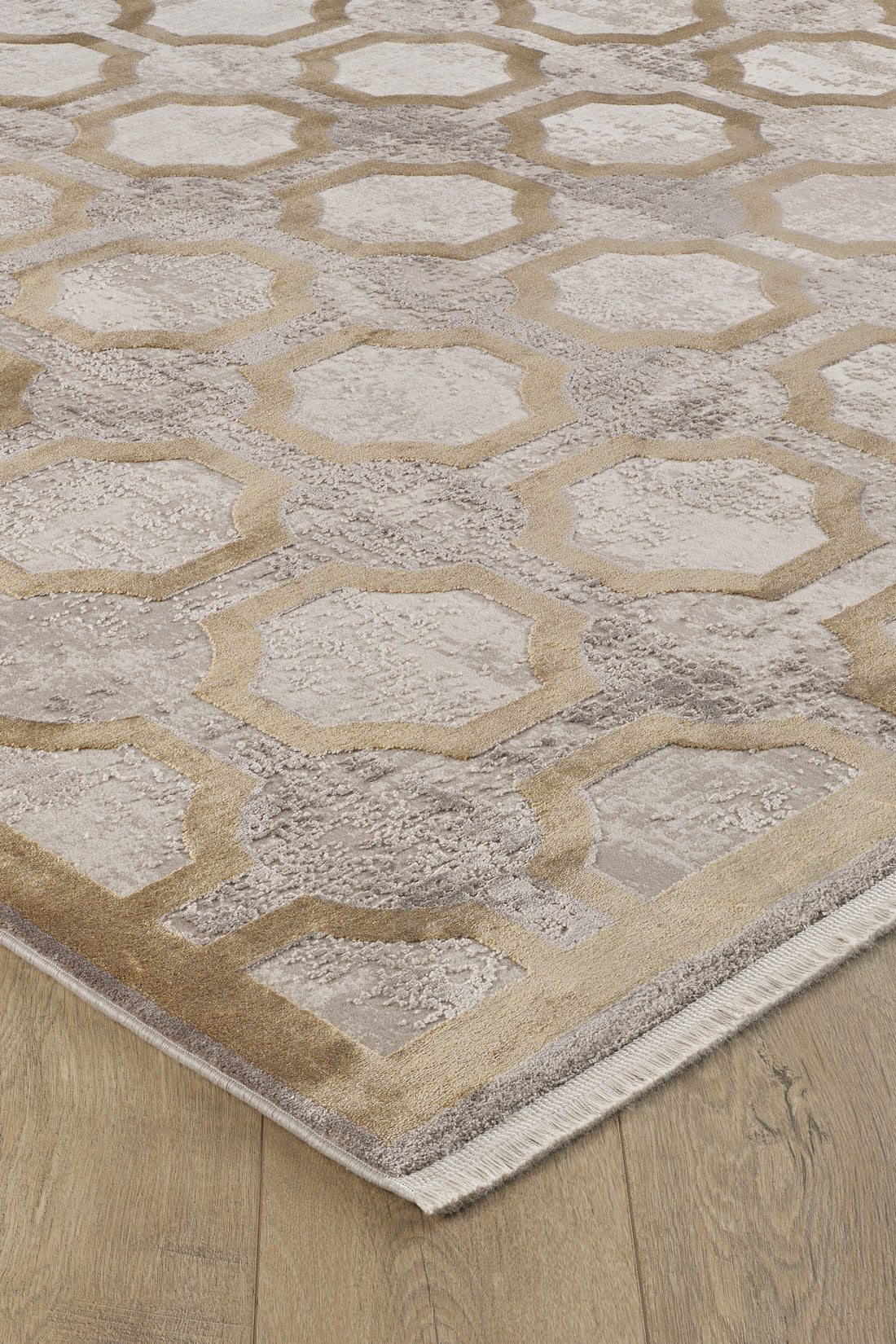 The Geometric Down Mid Century Modern Rug - M534B is a contemporary, machine-made beige and taupe rug with interlocking hexagon and octagon lattice patterns, featuring a short fringe on one edge and displayed on a light wood floor.