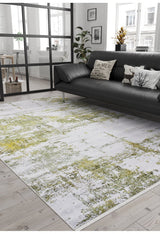 A modern living room features a black sofa, decorative pillows, plants, and large windows. The Geometric Geometry - Washable Rug - JR1290 in green adds a pop of color, while neutral tones and minimal decor create a cozy, stylish vibe.