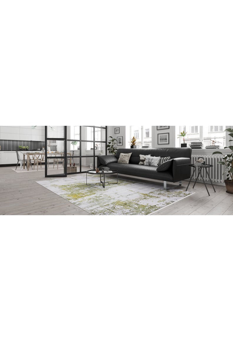 Modern living room featuring a black sofa, pillows, and the Geometric Geometry - Washable Rug - JR1290 (Custom Size), ideal for high-traffic areas. Large windows fill the space with light; dining area and kitchen visible through glass doors.