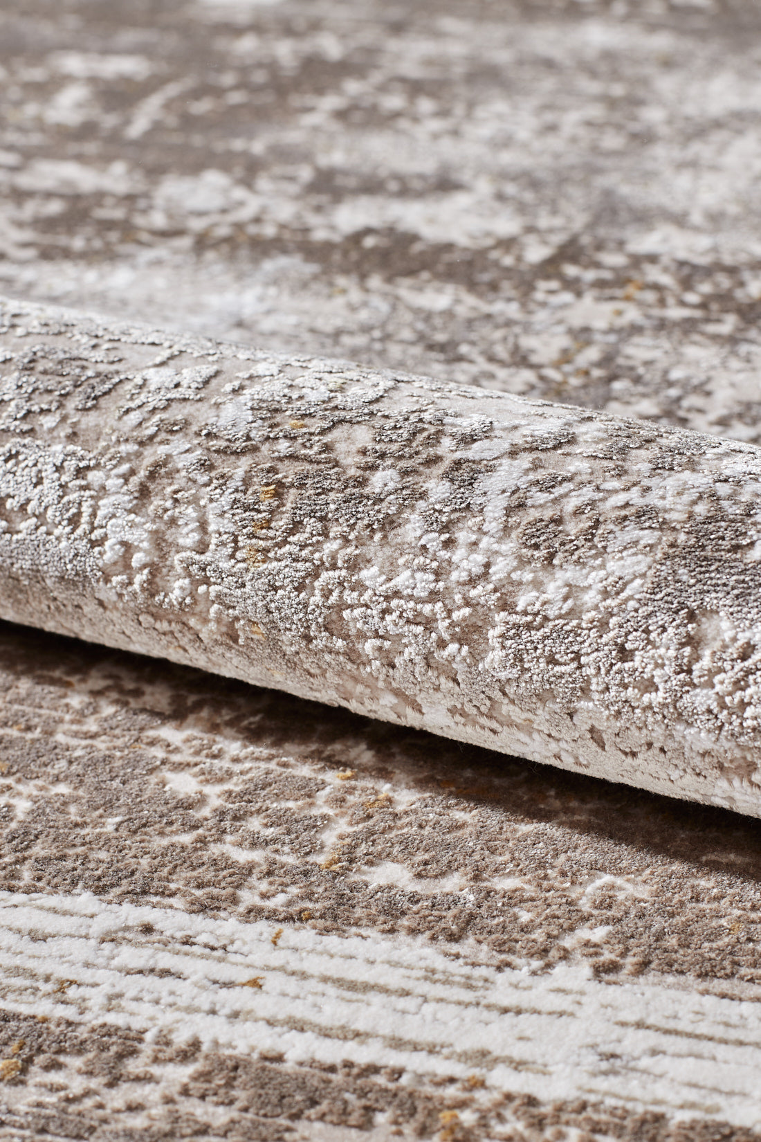 A close-up view of the Geometric Latte Premium Rug - M420G, a modern, machine-made rug in light beige and gray with a subtle abstract pattern and minimalist design.