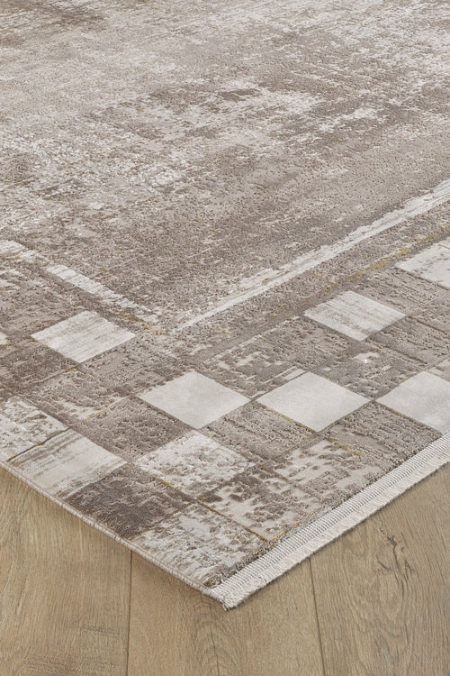 Load image 1 in gallery view. A close-up of the Geometric Latte Premium Rug - M420G, a machine-made beige and brown rug with a subtle geometric pattern and a border of light and dark squares, adds minimalist style to any light wood floor.