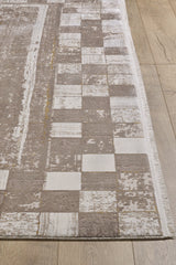 A close-up of the Geometric Latte Premium Rug - M420G shows its beige and cream checkered border on a light wooden floor. This machine-made rug blends textured and smooth surfaces for a chic, minimalist style.