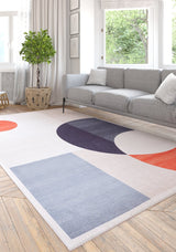 A modern living room features a gray sofa, white and gray pillows, a green potted plant, and the Geometric Zen Modern Washable Rug - MDJ002 with blue, orange, and purple shapes—perfect for allergy-sensitive spaces.