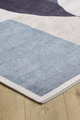 A close-up of the Geometric Zen Modern Washable Rug - MDJ002, allergy-sensitive and featuring a blue, purple, and beige geometric pattern with a zigzag-stitched edge for style and durability, shown on a light wooden floor.