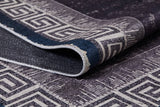 A close-up of the Geometric and Chic - Washable Rug - JR1273 (Custom Size), featuring a dark tone and white Greek key border pattern, partially folded to show front and back textures—perfect for high-traffic spaces.