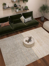 Modern living room featuring the Gilded Charm - Washable Rug - JRN26, a green velvet sofa with assorted cushions, round marble coffee table with decor, wall-mounted shelves with plants, and wooden floors.