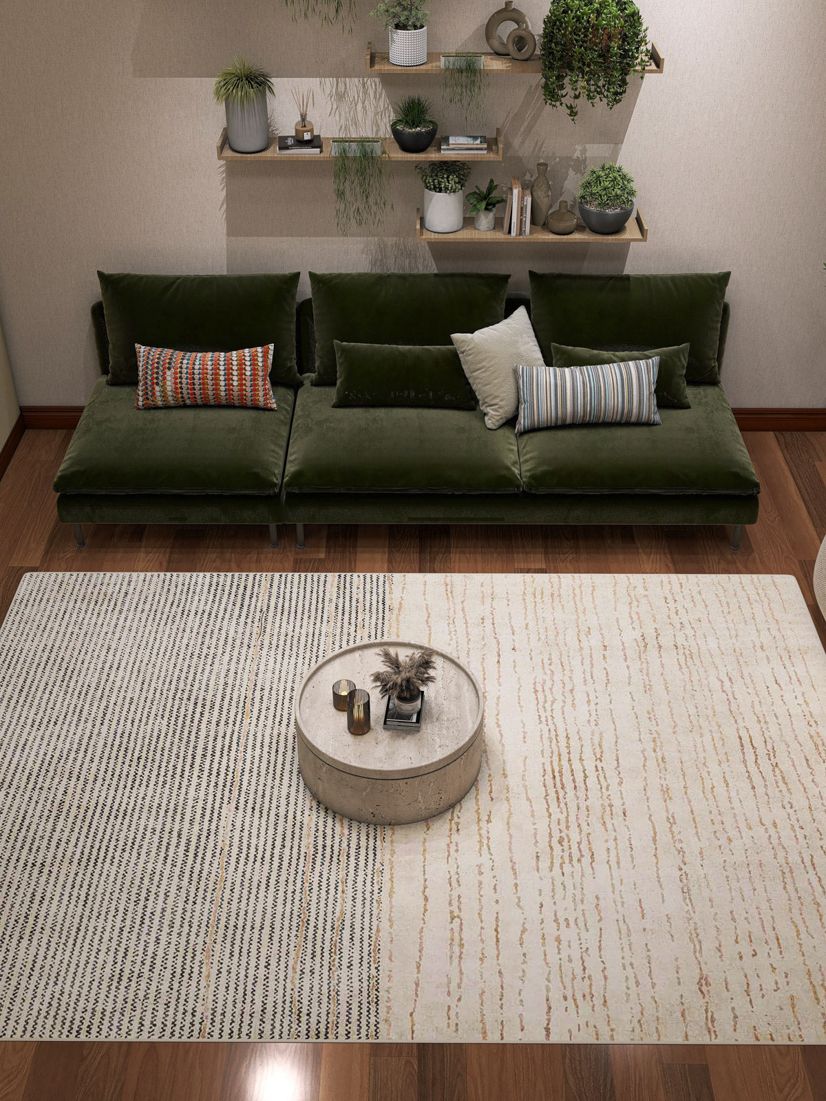 A modern living room features a green velvet sofa, mixed pillows, a round coffee table, and the Gilded Charm - Washable Rug - JRN26 (Custom Size), perfect for high-traffic areas. Wall shelves display potted plants and ornaments.