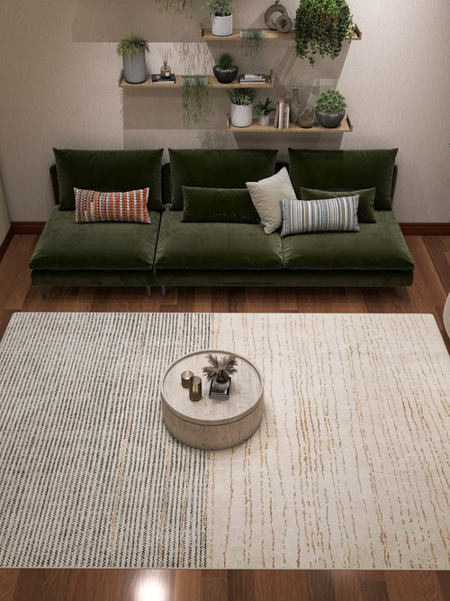 Load image 1 in gallery view. A modern living room features a green velvet sofa, mixed pillows, a round coffee table, and the Gilded Charm - Washable Rug - JRN26 (Custom Size), perfect for high-traffic areas. Wall shelves display potted plants and ornaments.