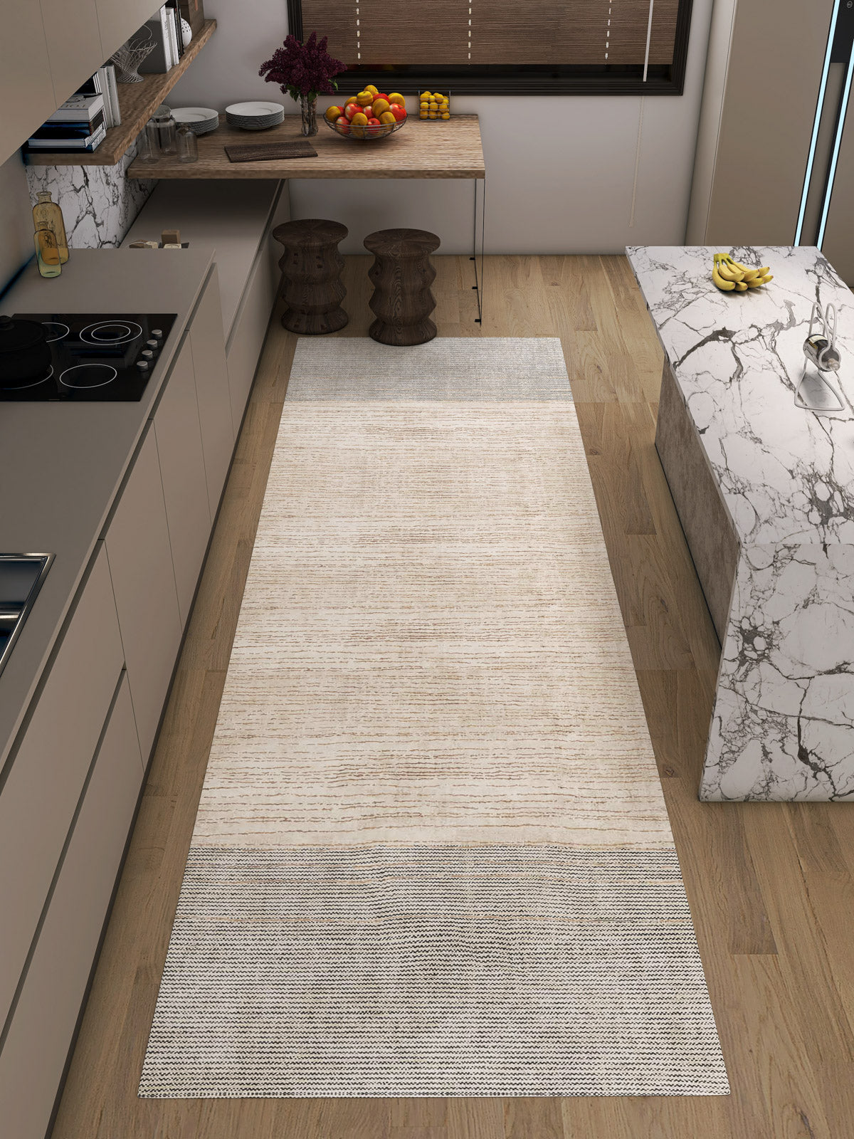 A modern kitchen with light wood floors features the Gilded Charm - Washable Rug - JRN26 (Custom Size), a flat weave beige and gray runner perfect for high-traffic areas, paired with marble counters, a stove, bar stools, fruit bowls, and brown blinds.
