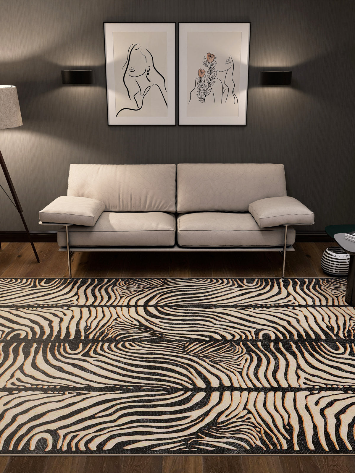 A modern living room features a beige sofa, abstract wall art, black wall lights, and the Gossamer Fade - Washable Rug - JRN44 with a zebra pattern on wooden floors. A floor lamp on the left provides soft light in this allergy-sensitive space.