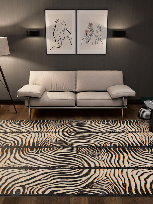 Load image 1 in gallery view. A modern living room features a beige sofa, abstract wall art, black wall lights, and the Gossamer Fade - Washable Rug - JRN44 with a zebra pattern on wooden floors. A floor lamp on the left provides soft light in this allergy-sensitive space.