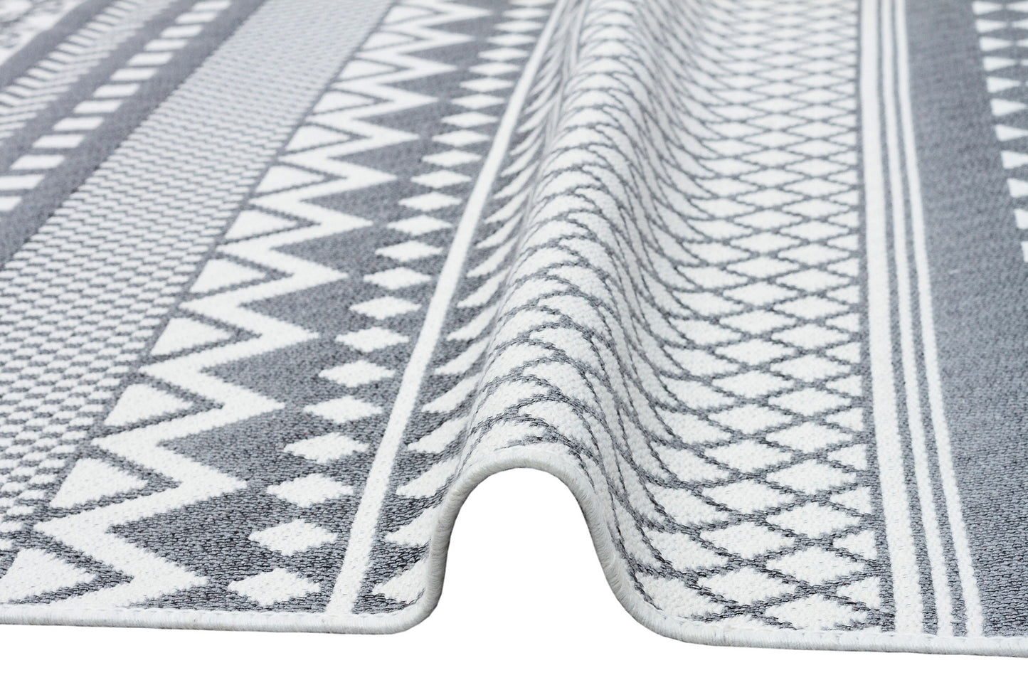 A close-up of the Grey Drift - Washable Reversible Kilims - AR07 shows a grey geometric kilim with tribal accents and a raised, wavy fold down the center.