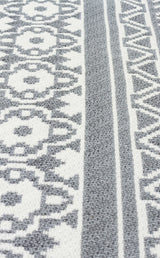 Close-up of the Grey Drift - Washable Double-Sided Kilims - AR07, a textured grey rug with white geometric patterns—triangles and circles—in vertical stripes. This allergy-friendly rug is designed for comfortable living and easy washing.