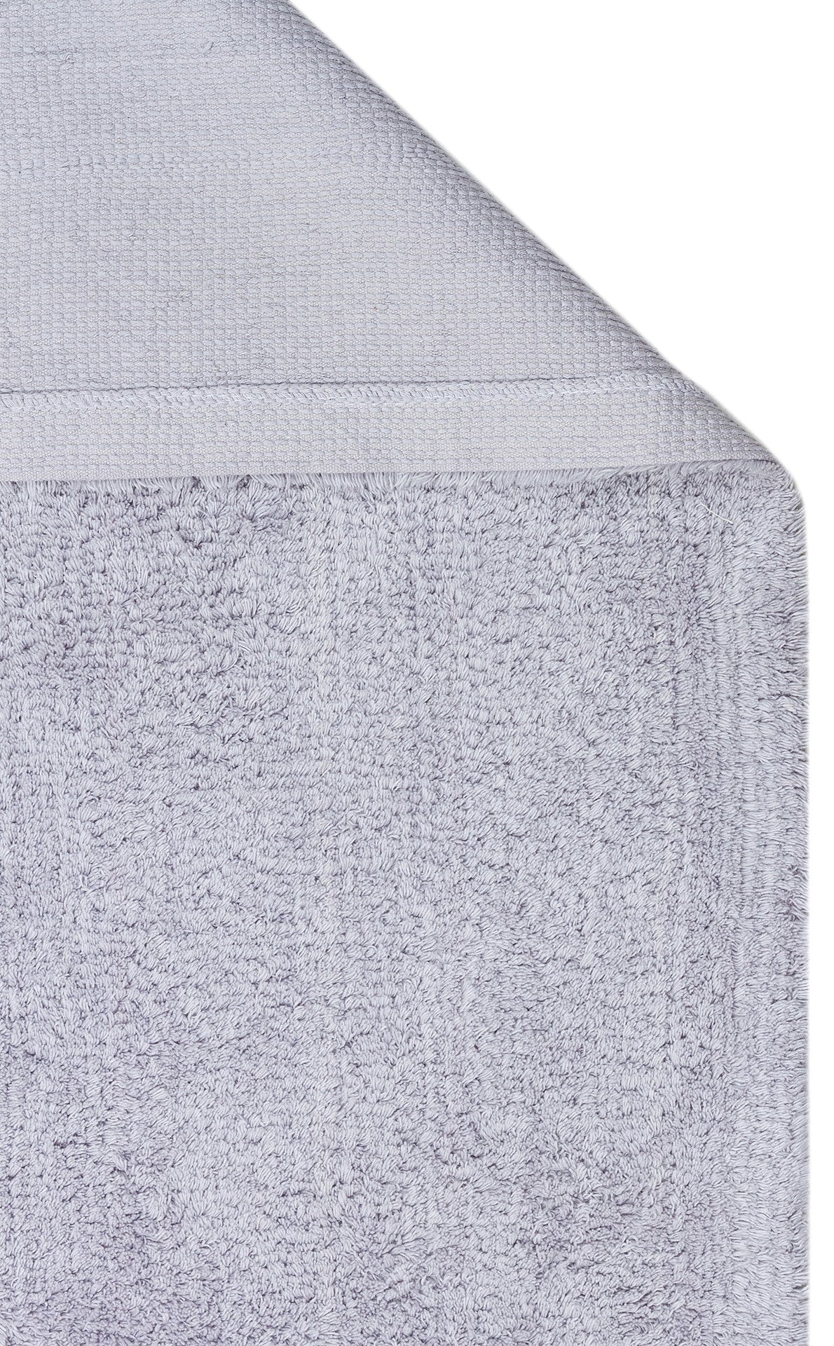 A close-up of the Grey Snug - Washable Shaggy - CBNPLAIN, neatly folded to display its soft, textured fabric and woven border—perfect for adding a cozy, coordinated touch to any modern bedroom or grey cotton rug ensemble.