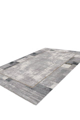 The GridWave Silver Premium Rug - M426A is a rectangular, machine-made rug with a minimalist gray distressed pattern, lighter and darker blocks, and a subtle border. Modern in style, it's shown on a white background.