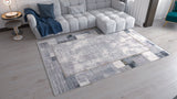 A modern living room with a white sectional, blue pillows and throw, side table with lamp, and the GridWave Silver Premium Rug - M426A featuring a distressed pattern on light wooden flooring.