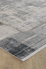 A close-up of the GridWave Silver Premium Rug - M426A, featuring a textured, abstract gray and beige pattern on a light wooden floor. This machine-made rug offers a modern minimalist look with neat edges and a slightly distressed finish.