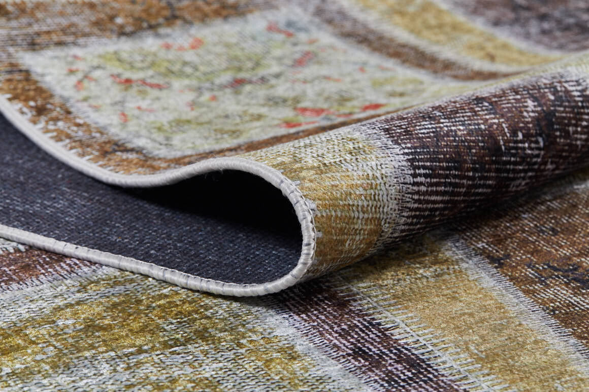 A close-up of the Gridiron Glow - Washable Rug - JR183 (Custom Size) highlights its folded, stitched edge and abstract earth-toned patterns—ideal for high-traffic areas and easy to clean.