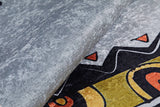 Close-up of the Groovy Bear - Machine-Washable Rug JRC093 (Custom Size), folded to reveal its colorful geometric black, yellow, orange, and red pattern on a gray-anthracite background. Stylish and easy to maintain.