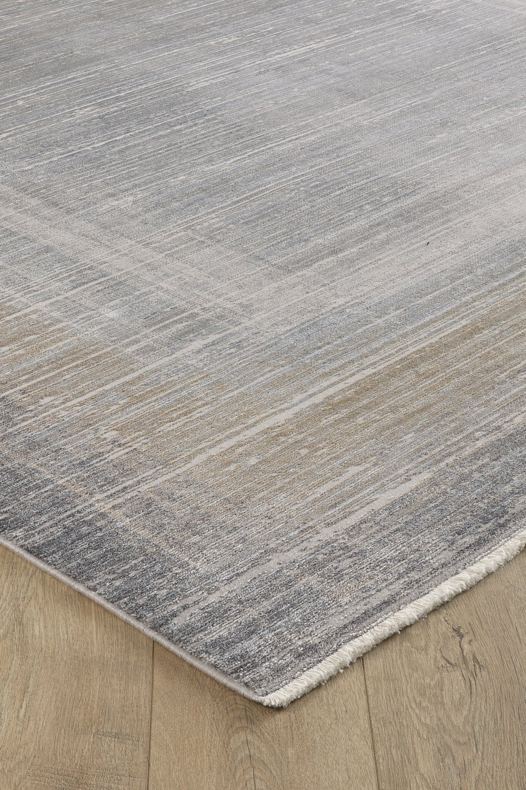 A close-up of the Harmony in Contours Modern Bordered Rug - EW5743, featuring a subtle gray and beige gradient, minimalist design, slight texture, machine-made quality, fringe detailing, and set on a light wood floor.