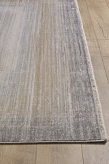 A close-up of the Harmony in Contours Modern Bordered Rug - EW5743, a machine-made rug with a subtle linear pattern in beige, gray, and cream on a light brown wooden floor. Minimalist design with short fringe on one edge.