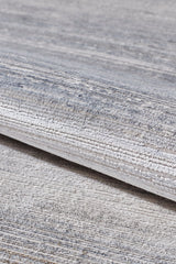 A close-up of the Harmony in Contours Modern Bordered Rug - EW5743 shows its minimalist, light gray machine-made design with subtle horizontal patterns, partially rolled on a matching gray surface.