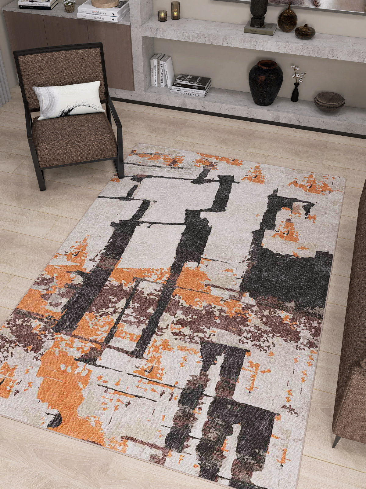 A modern living room with a brown chair, beige shelves with decor, and the Heirloom Touch - Washable Rug - JRN42 (Custom Size) featuring black, orange, and beige patterns on a light wood floor.