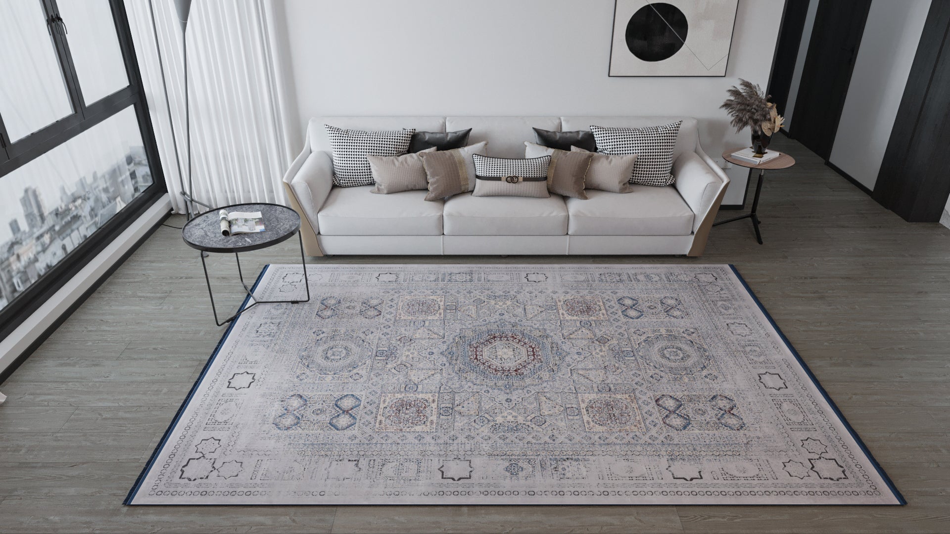 A modern living room features a light sofa with cushions, round side tables, white curtains on a large window, and abstract art above. The Hidden Treasures Turkish Rug - Smoky - 2223C adds patterned style underfoot.