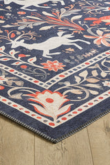 A close-up of the Holiday Heart Washable Area Rug - MDJ001, featuring a dark blue background with white animal silhouettes, orange and beige floral patterns, and a stitched edge—ideal for high-traffic areas on light wood floors.