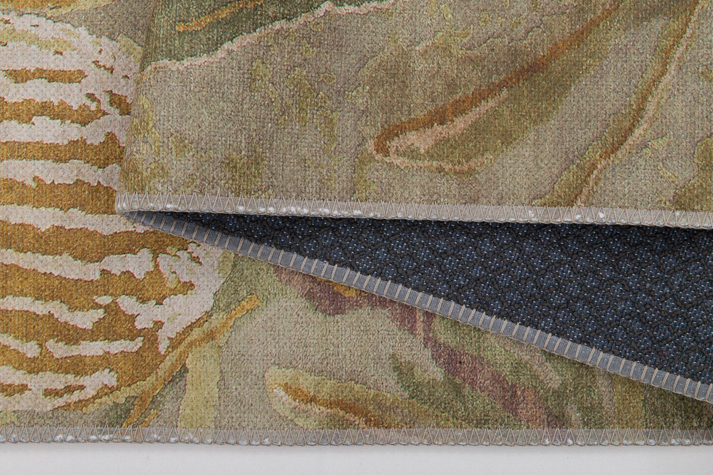 A close-up of the Dreamweaver's Loom - Washable Rug - JRS001 (Custom Size) in muted earth tones, perfect for high-traffic areas, with a flipped corner revealing its dark, textured non-slip backing.