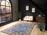 A modern living room with a large arched window, the Imperial Medallion - Washable Rug - JRN1006 in blue, a cream sofa, plants, wall clock, framed botanical prints, wooden floors, black-railed staircase and a city view.