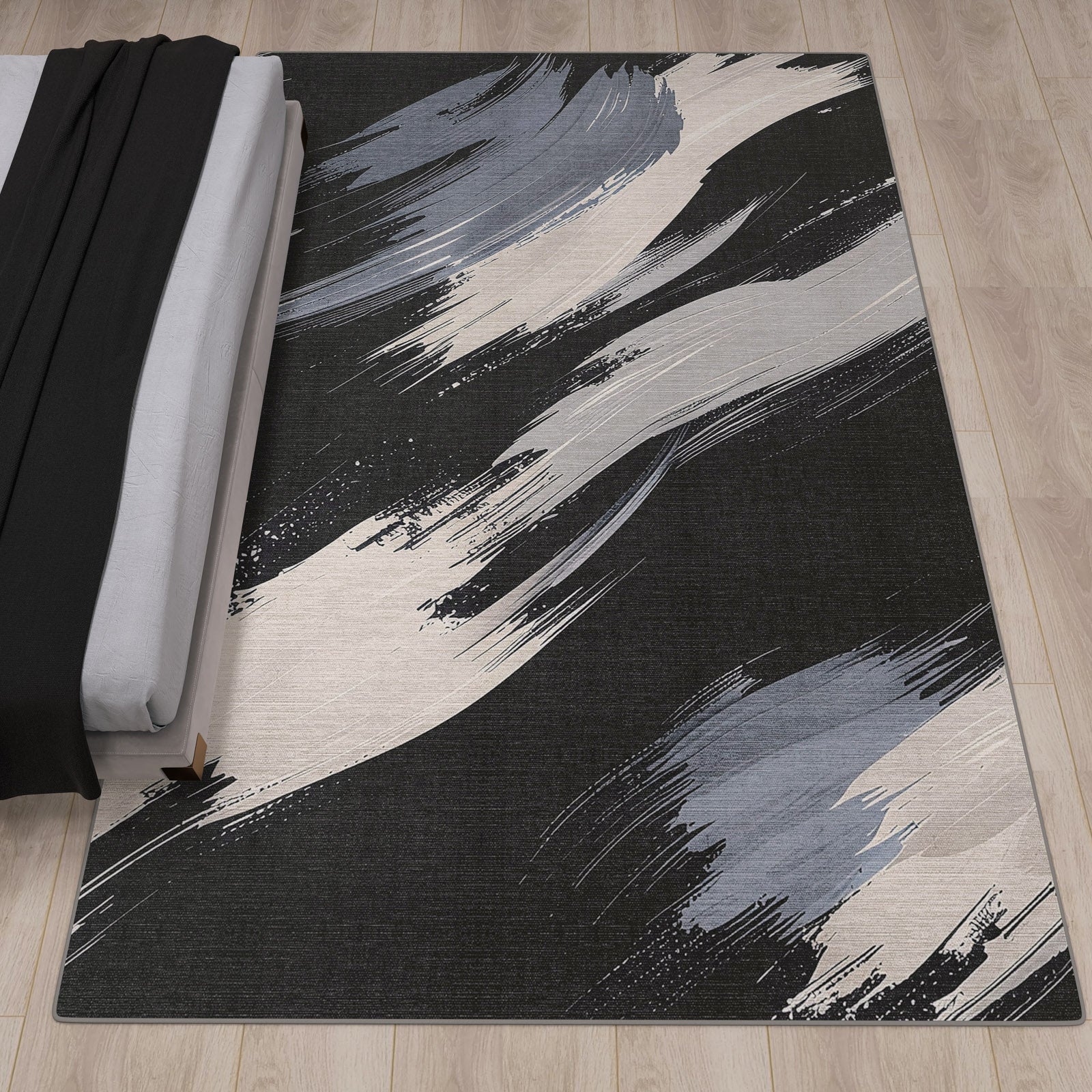 The Shadow Flow - Washable Rug - JRS011 (Custom Size) features abstract black, gray, and white brushstroke patterns and is ideal for high-traffic areas, shown here on a light wood floor beside a neatly made bed.