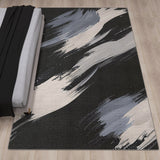 The Shadow Flow - Washable Rug - JRS011 (Custom Size) features abstract black, gray, and white brushstroke patterns and is ideal for high-traffic areas, shown here on a light wood floor beside a neatly made bed.