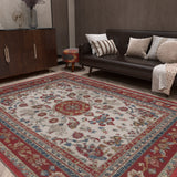 A living room with a dark brown sofa topped with assorted cushions, a wood cabinet, and the Imperial Rose - Washable Rug - JRS023 featuring red, blue, and beige floral patterns. A patterned round ottoman sits near the sofa.