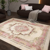 A living room with a dark brown sofa, pink and white pillows, a gray throw, a potted plant, and the Petal Mist - Washable Rug - JRS025 showcasing pink, cream, and floral patterns on a dark wood floor—ideal for modern spaces.