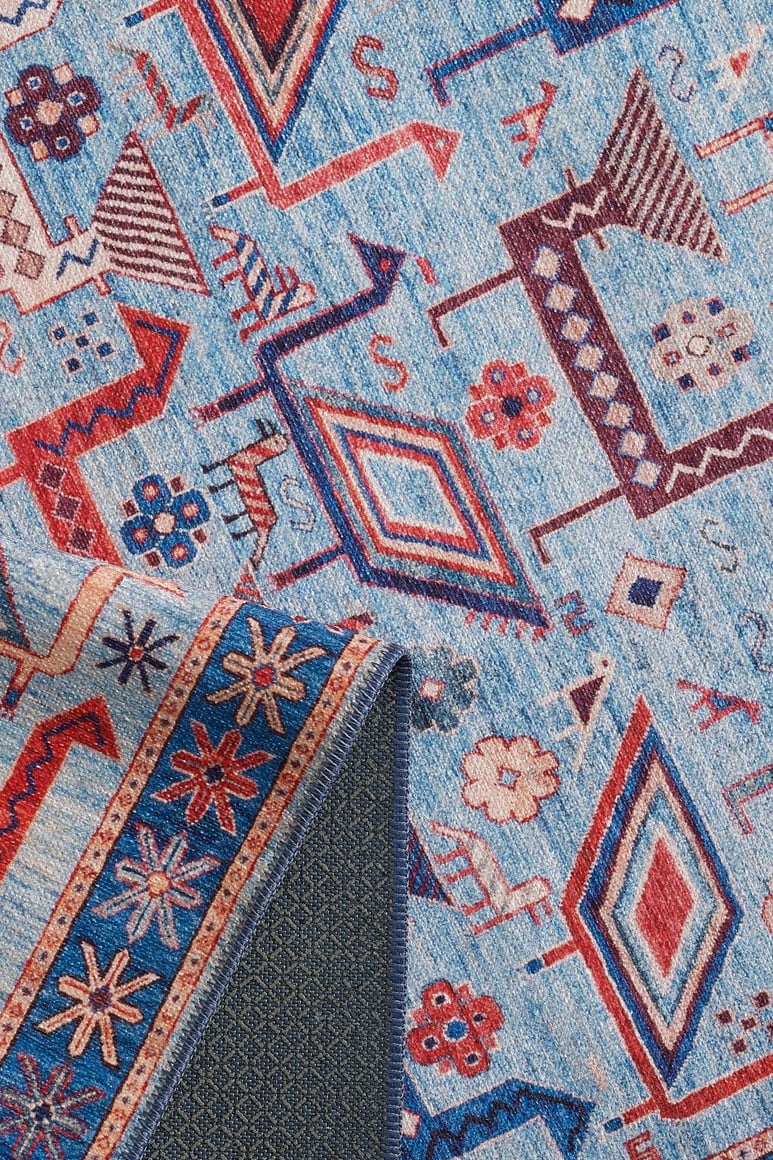 The Birdwatcher's Dream Blue Washable Rug - LCC3020 features geometric and floral patterns in red, blue, and cream. A folded corner reveals a blue and orange star design on the back—perfect for high-traffic areas.