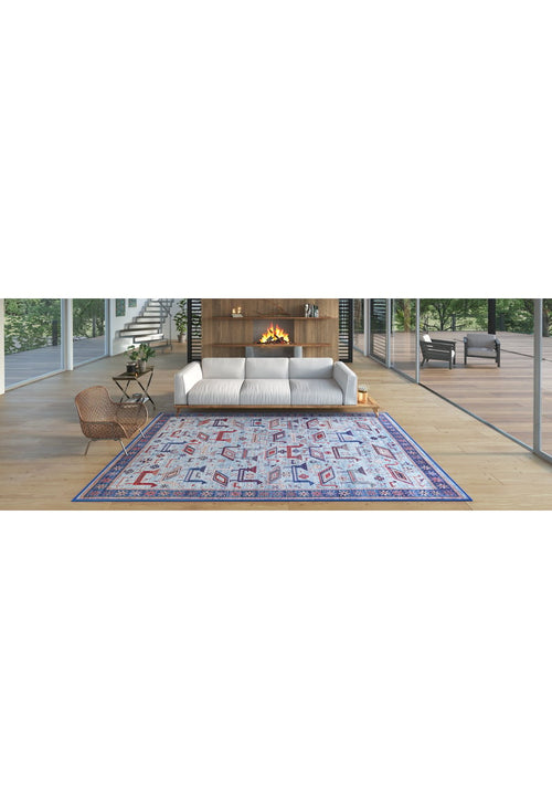 Load image 1 in gallery view. Modern living room with a white sofa, wooden floor, Birdwatcher's Dream Blue Washable Rug - LCC3020 ideal for high-traffic areas, cozy fireplace, and large glass windows overlooking greenery. Wicker chair and small table sit to the left.