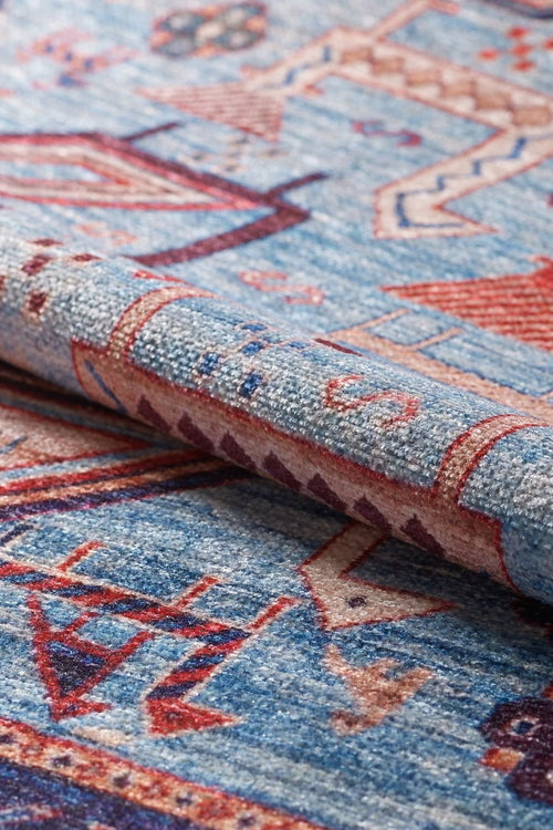Load image 1 in gallery view. A close-up of the Birdwatcher's Dream Blue Washable Rug - LCC3020, featuring red and beige geometric designs, highlights its textured fabric and a folded edge—ideal for high-traffic areas.