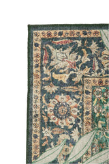 Close-up of the Jungle Ember - Washable Rug (JR0047): ornate, vintage-style with a dark floral pattern, green border, and cream background. Large light green leaves partially cover its edge.