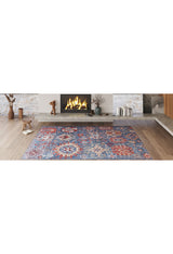 A cozy living room features the Kaleidos Authentic Blue Washable Rug (LCC3028) with colorful patterns on light wooden floors—a modern touch for high-traffic areas. Decorative items and logs sit on a wide concrete mantel by the lit fireplace.