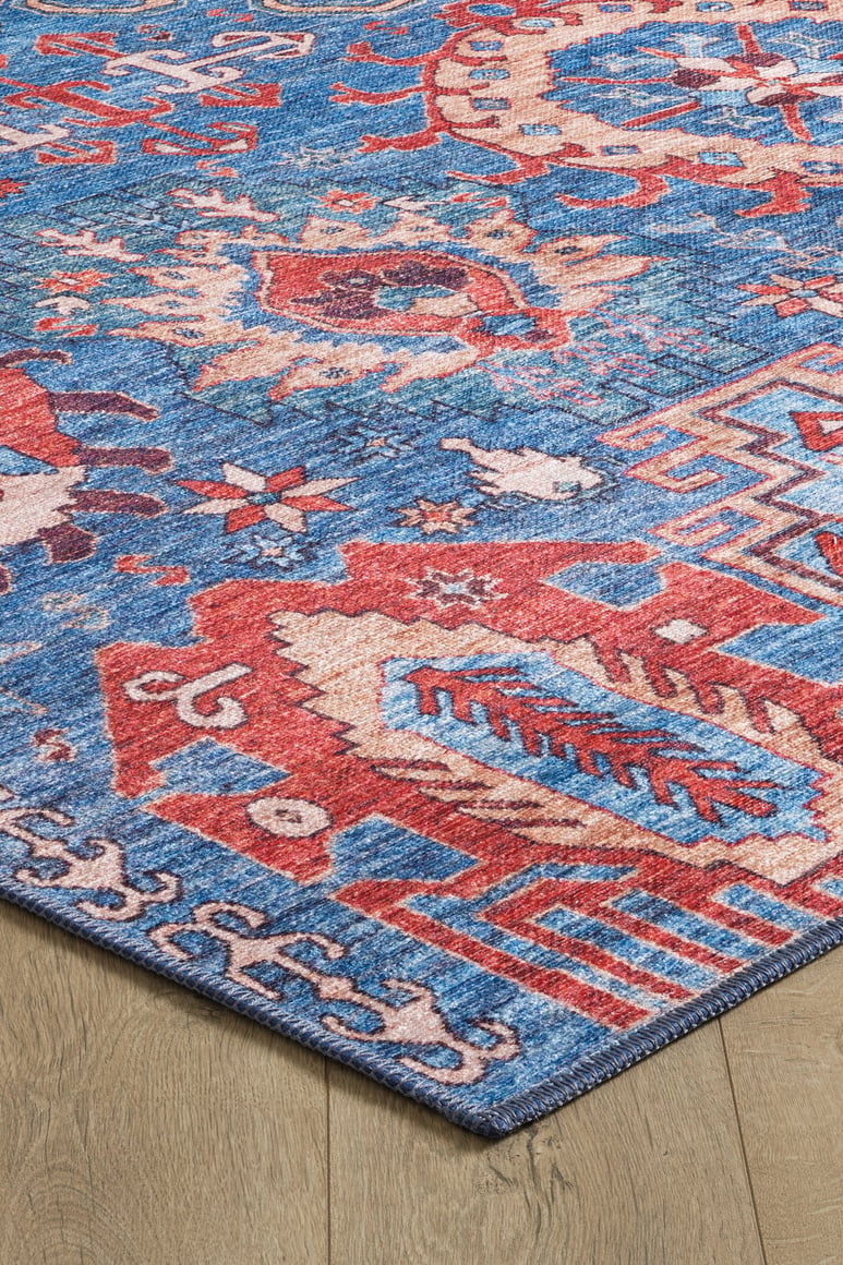 A close-up of the Kaleidos Authentic Blue Washable Rug - LCC3028 (Custom Size), featuring vibrant red and cream geometric patterns on blue, highlights its textured design and durability for high-traffic areas on a wooden floor.