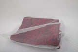 A red and black patterned fabric is partially covered by the Laundry Washing Bag, a white drawstring bag set on a plain background—ideal for protecting washable rugs during cleaning.