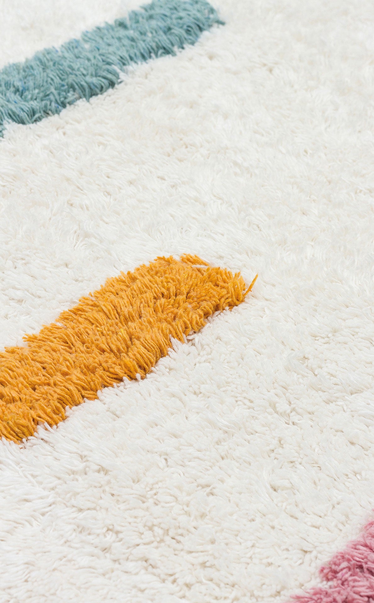 A close-up of the Little Steps - Washable Shaggy - CBN03 rug, featuring a soft white base with thick teal, yellow, and pink stripes. This multicolour shaggy rug's fluffy texture is ideal for brightening any children’s room.