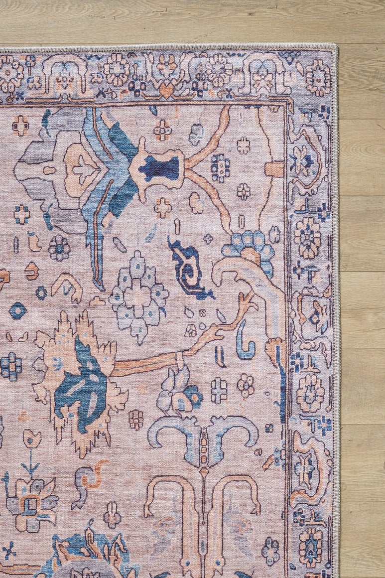 A close-up of the Luminary Beige Gray Washable Rug (LCC3023) shows its ornate flat weave with pink, blue, and cream accents in intricate floral and geometric patterns on a light wooden floor.