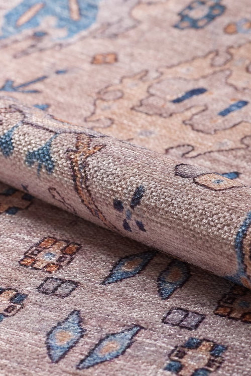 Bild 1 in Galerieansicht laden. A close-up of the Luminary Beige Gray Washable Rug (LCC3023), rolled up to reveal its textured flat weave and intricate geometric and floral patterns in beige, blue, and brown tones.