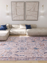 A bright living room with cream sofas, blue accent pillows, a Luminary Beige Gray Washable Rug - LCC3023 (Custom Size) for high-traffic areas, two abstract beige wall art pieces, and modern wall sconces.