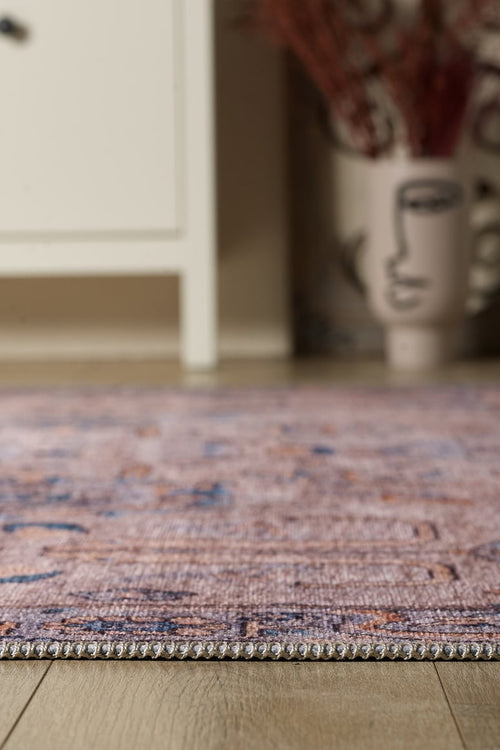 Bild 1 in Galerieansicht laden. A close-up of the Luminary Beige Gray Washable Rug (LCC3023 Custom Size) on a wooden floor, with a white cabinet and an abstract face vase with dried plants in the background—ideal for high-traffic spaces.