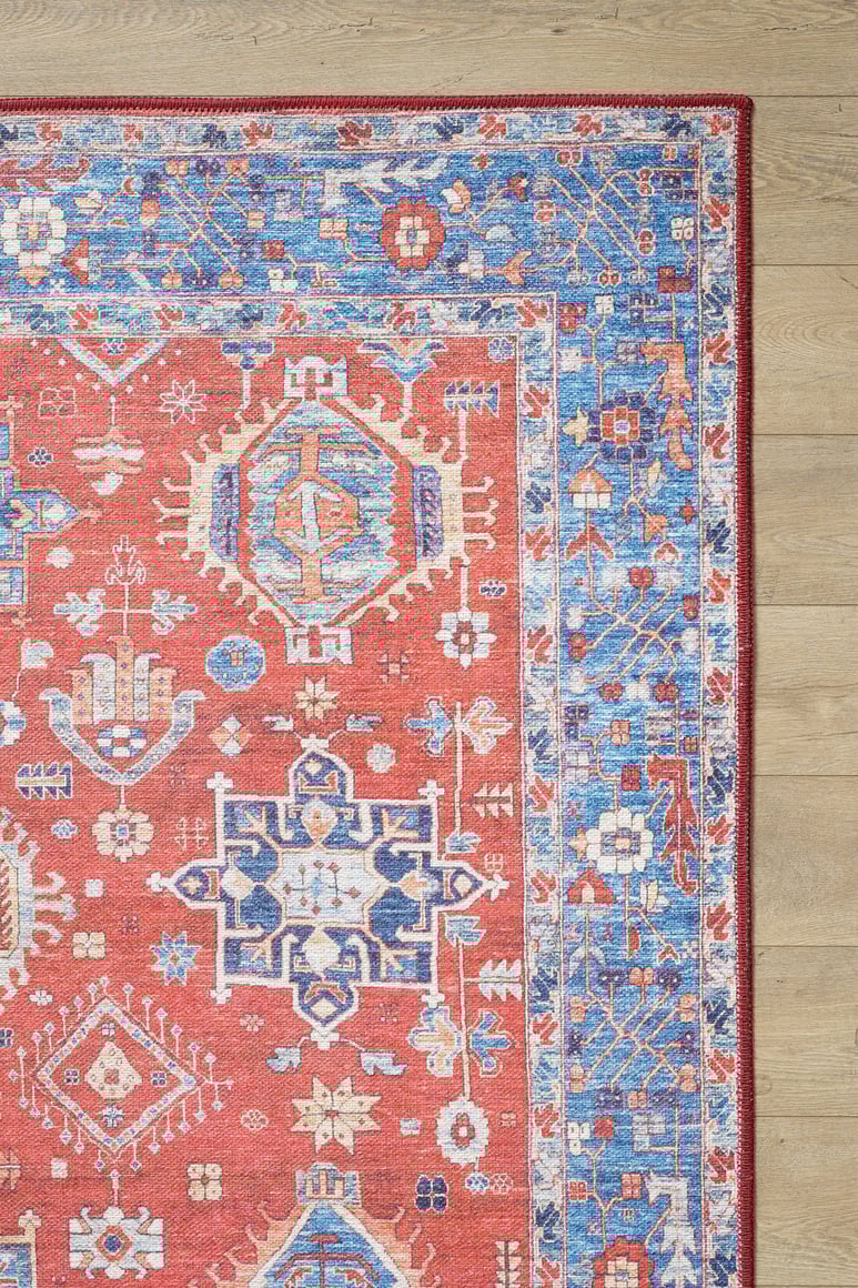 The Lunavale Red Blue Washable Rug - LCC3007, with a red center and blue border featuring intricate geometric and floral patterns in white, blue, and gold, lies on a light wood floor—ideal for high-traffic areas.